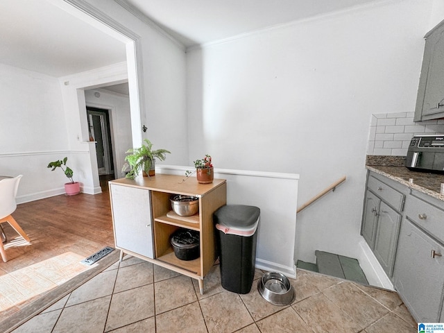 kitchen featuring light tile patterned floors, gray cabinets, tasteful backsplash, and ornamental molding