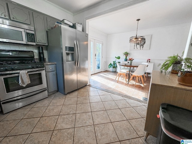 kitchen with tasteful backsplash, ornamental molding, stainless steel appliances, decorative light fixtures, and light tile patterned flooring