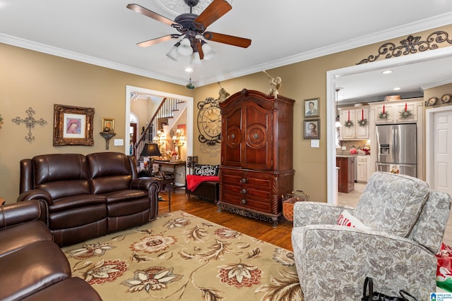 living room with crown molding, ceiling fan, and light wood-type flooring