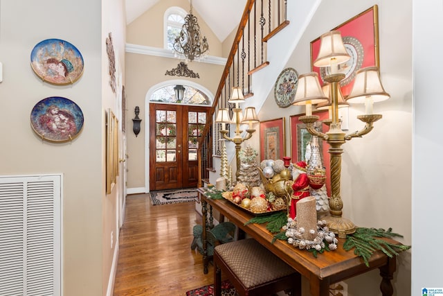 foyer with hardwood / wood-style floors, plenty of natural light, high vaulted ceiling, and french doors