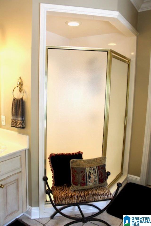 bathroom featuring vanity, a shower with door, and crown molding