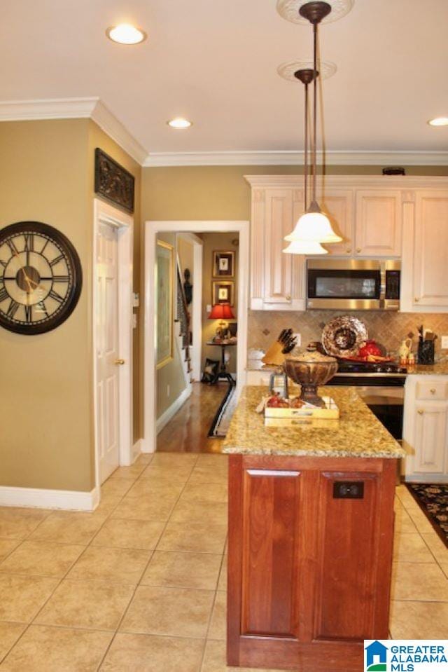 kitchen featuring light stone countertops, appliances with stainless steel finishes, ornamental molding, light tile patterned floors, and decorative light fixtures