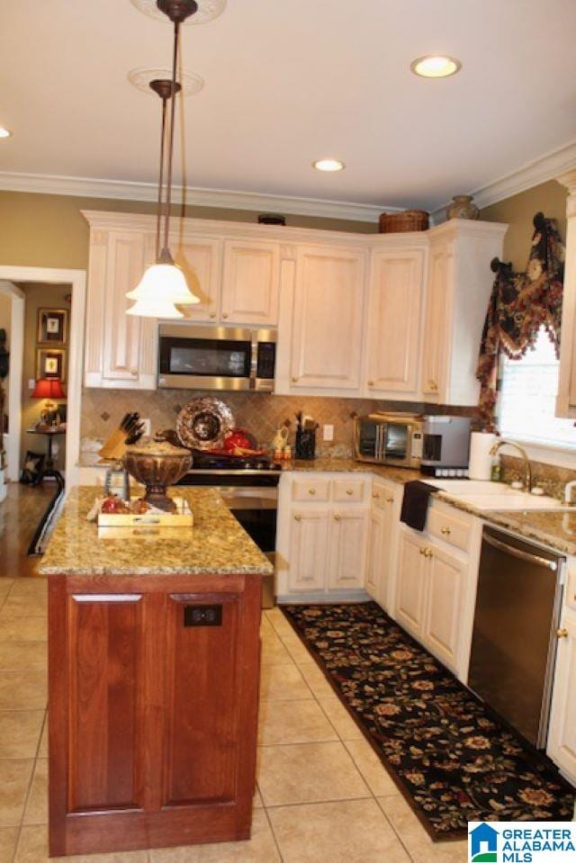 kitchen with light stone counters, hanging light fixtures, light tile patterned floors, and stainless steel appliances