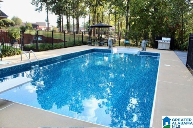 view of pool with area for grilling and a diving board