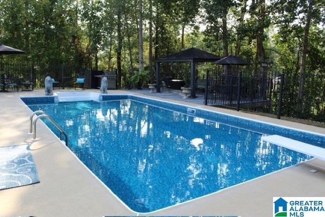 view of pool featuring a gazebo, a diving board, and a patio area