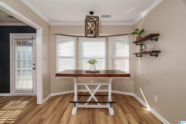 dining area with crown molding, light hardwood / wood-style floors, and a notable chandelier