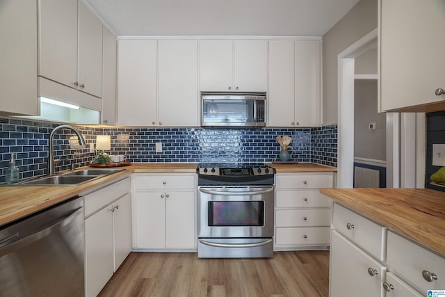 kitchen featuring sink, butcher block countertops, backsplash, white cabinets, and appliances with stainless steel finishes