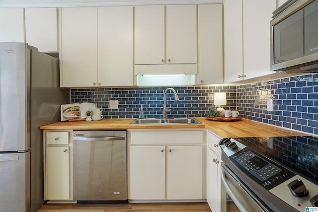 kitchen featuring wooden counters, white cabinets, sink, decorative backsplash, and appliances with stainless steel finishes