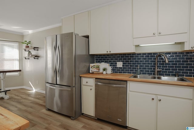 kitchen with white cabinets, appliances with stainless steel finishes, wooden counters, and sink