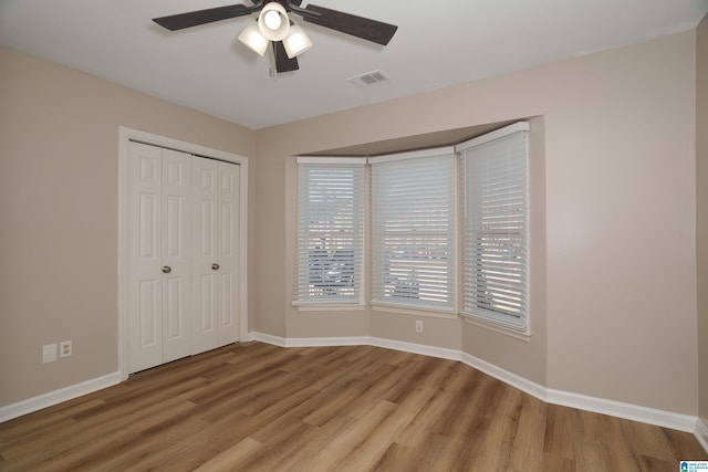 unfurnished bedroom featuring ceiling fan, wood-type flooring, and a closet