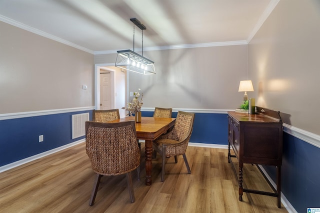 dining area with hardwood / wood-style flooring and ornamental molding