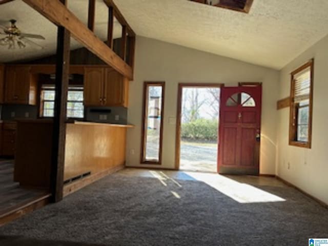 kitchen featuring vaulted ceiling, ceiling fan, dark carpet, and a textured ceiling