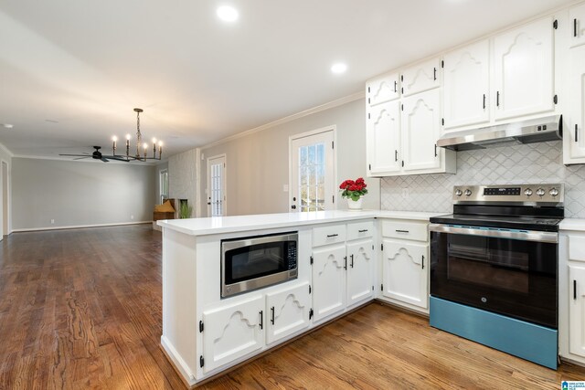 kitchen with kitchen peninsula, stainless steel appliances, crown molding, white cabinetry, and hanging light fixtures