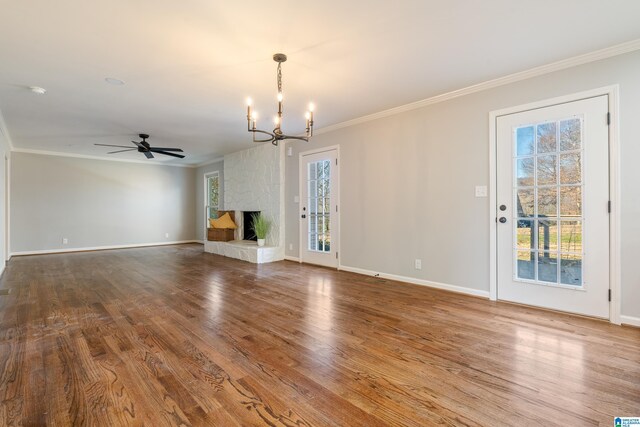 unfurnished living room with a stone fireplace, crown molding, hardwood / wood-style floors, and ceiling fan with notable chandelier