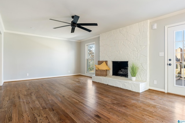 unfurnished living room featuring hardwood / wood-style flooring, ceiling fan, a stone fireplace, and crown molding