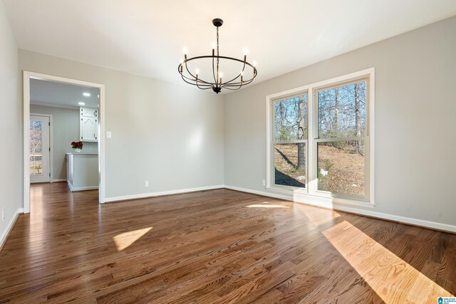 unfurnished dining area featuring dark hardwood / wood-style flooring and an inviting chandelier