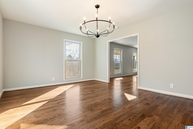 spare room featuring a chandelier and dark hardwood / wood-style flooring