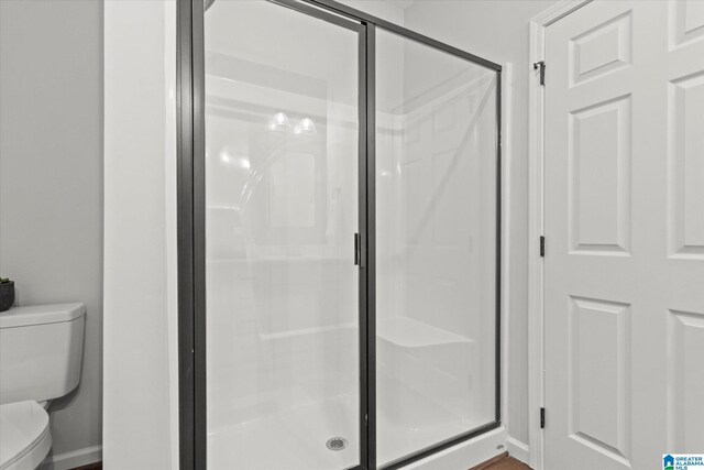 full bathroom with baseboards, a shower stall, and toilet