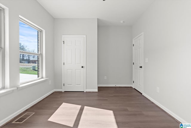 unfurnished bedroom featuring baseboards, visible vents, and dark wood-type flooring