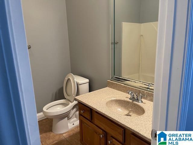 bathroom featuring tile patterned flooring, vanity, toilet, and walk in shower