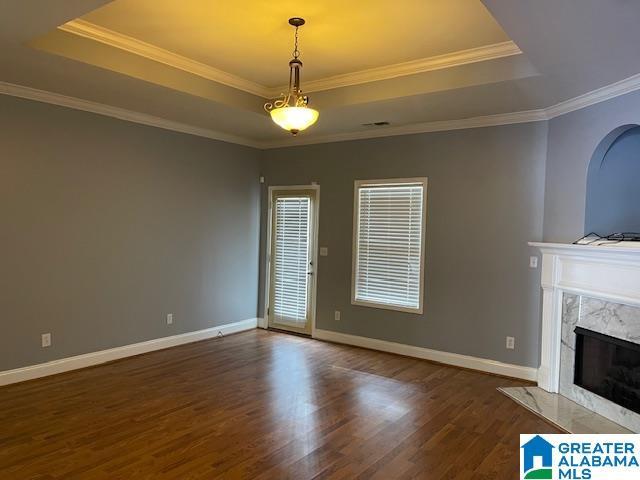 unfurnished living room featuring a raised ceiling, crown molding, and a high end fireplace