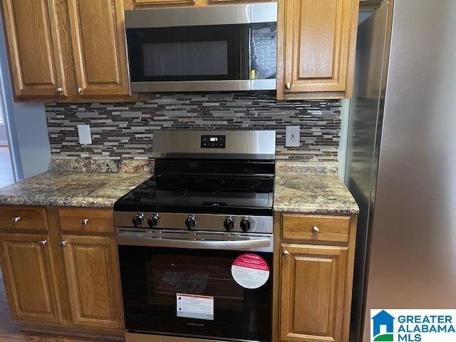 kitchen featuring decorative backsplash, light stone counters, and stainless steel appliances