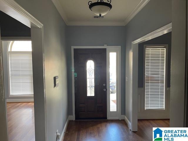 foyer featuring crown molding and dark wood-type flooring