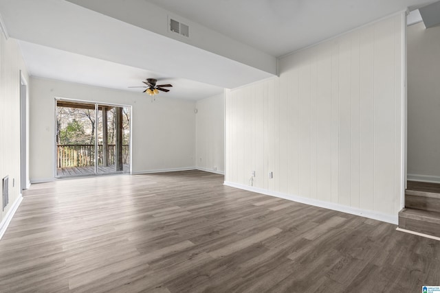 unfurnished room featuring ceiling fan, dark wood-type flooring, and wood walls