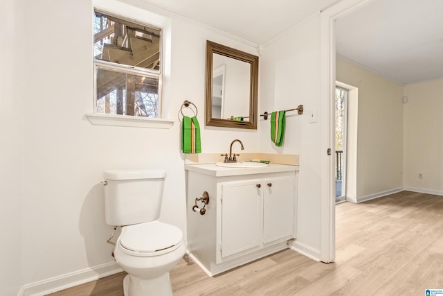 bathroom with hardwood / wood-style floors, vanity, toilet, and ornamental molding