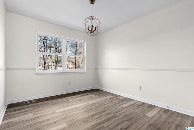 empty room featuring hardwood / wood-style floors and a chandelier