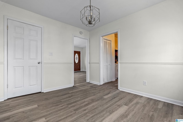 spare room featuring a chandelier and hardwood / wood-style flooring