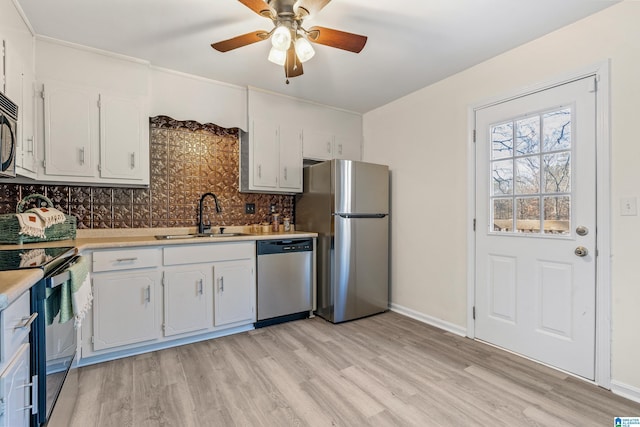 kitchen featuring backsplash, sink, light wood-type flooring, white cabinetry, and stainless steel appliances