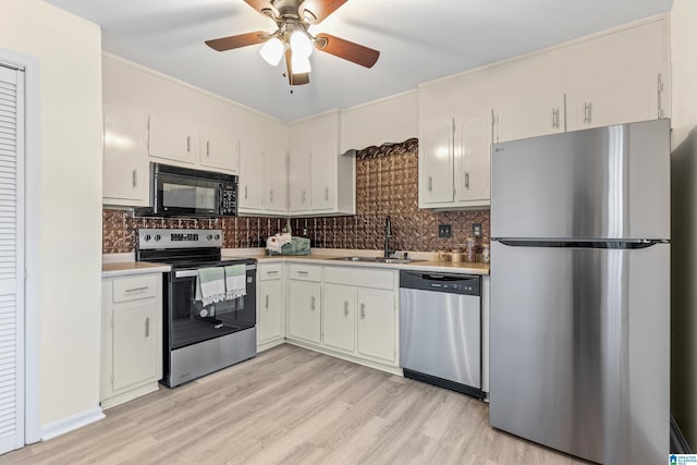 kitchen featuring sink, ceiling fan, light wood-type flooring, appliances with stainless steel finishes, and white cabinetry