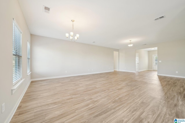 spare room featuring a notable chandelier and light wood-type flooring