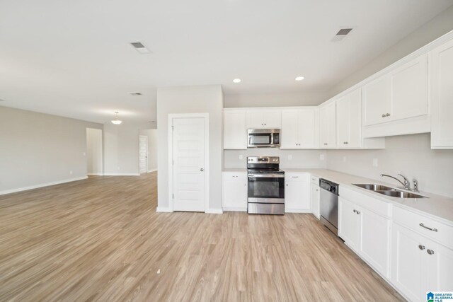 kitchen with white cabinets, appliances with stainless steel finishes, light wood-type flooring, and sink