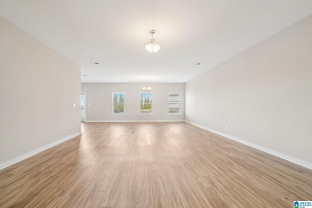 unfurnished living room with a chandelier and light hardwood / wood-style floors