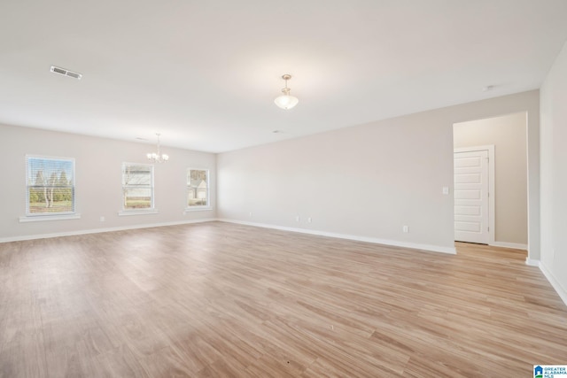 unfurnished room featuring light wood-type flooring and an inviting chandelier