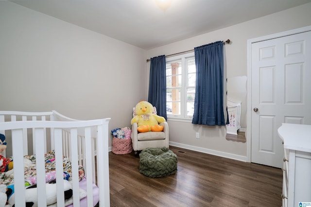 bedroom featuring dark hardwood / wood-style flooring and a nursery area