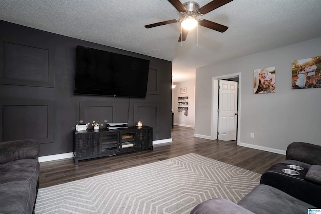 living room featuring ceiling fan, dark hardwood / wood-style flooring, and a textured ceiling