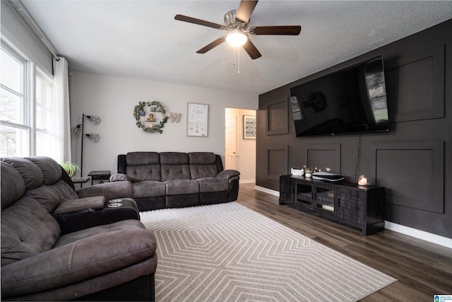 living room with a textured ceiling, ceiling fan, and dark hardwood / wood-style floors