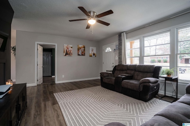 living room with a textured ceiling, plenty of natural light, ceiling fan, and dark wood-type flooring