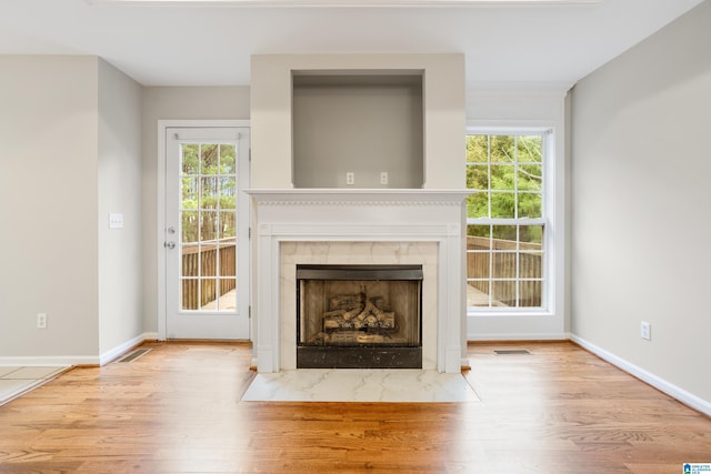 unfurnished living room with a fireplace, light wood-type flooring, and plenty of natural light