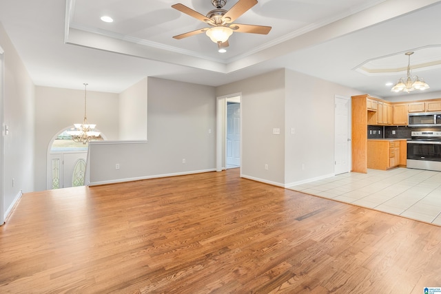 unfurnished living room with a raised ceiling, light wood-type flooring, and ornamental molding