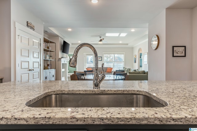 kitchen featuring light stone countertops, sink, and ceiling fan