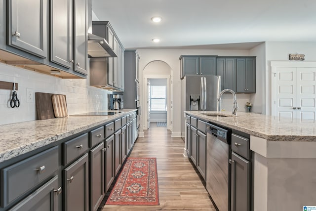 kitchen with gray cabinetry, sink, light stone countertops, tasteful backsplash, and stainless steel appliances