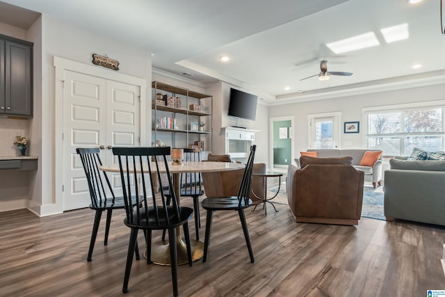 dining room with dark hardwood / wood-style floors, a raised ceiling, and ceiling fan