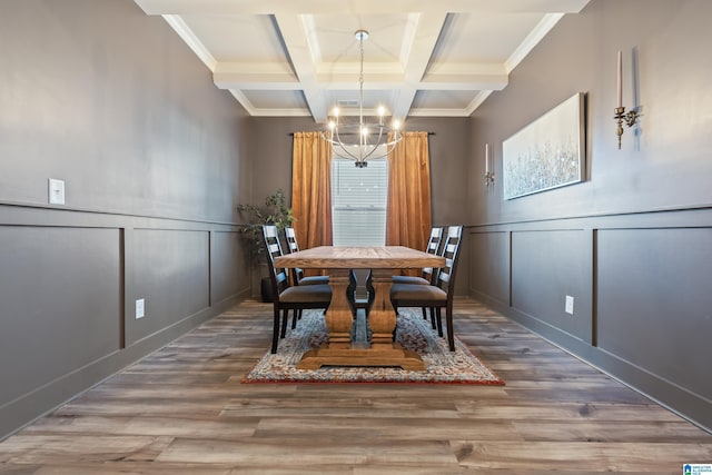 dining room featuring beam ceiling, wood-type flooring, ornamental molding, and a chandelier