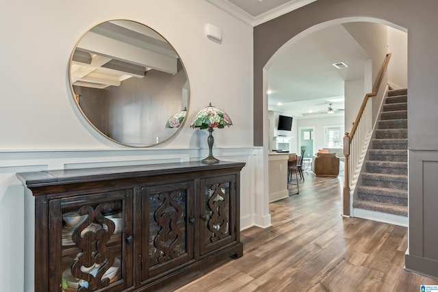 hallway featuring hardwood / wood-style floors, beamed ceiling, and ornamental molding