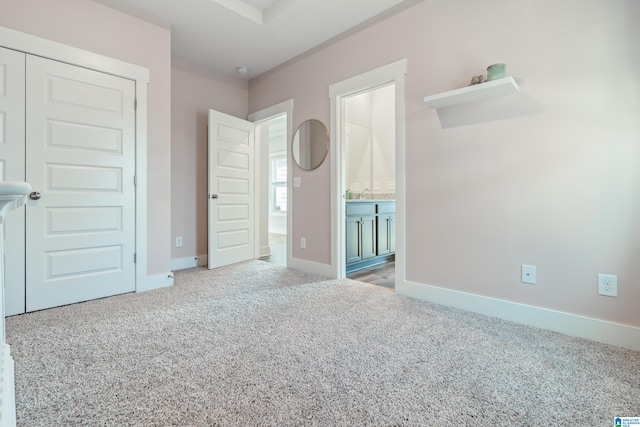 unfurnished bedroom featuring light carpet, ensuite bathroom, a closet, and sink