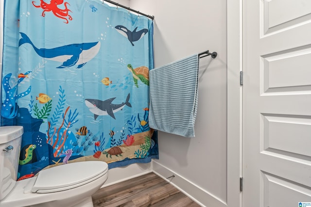 bathroom with curtained shower, toilet, and wood-type flooring